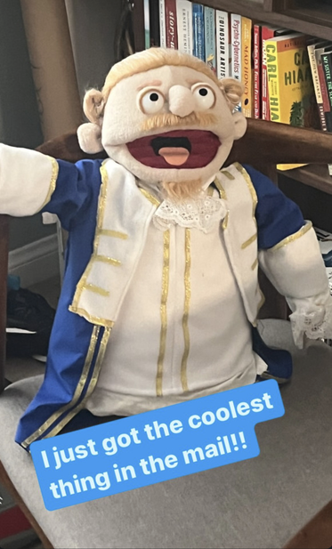 Instagram Story from AlexJ_Sherman: photo of a muppet of Alex Sherman's character from the OFMD season 2 finale, the British soldier whose bare ass is shown after the battle at Spanish Jackie's. The muppet has a blond goatee and mustache, and it is wearing a curly blond wig, a lace jabot and a blue coat with white lapels and cuffs and gold trims. Alex's caption at the bottom of the photo reads, “I just got the coolest thing in the mail!!”