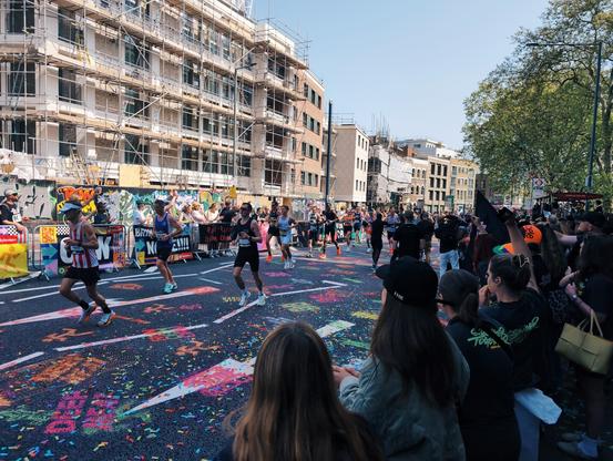 London marathon runners at mile 21 with the road decorated with paint and confetti