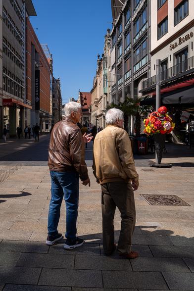 Zwei ältere Herren mit weißen Haaren auf einer Straße im Zentrum Leipzigs.