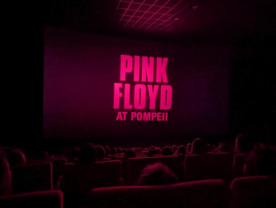Cinema screen: "PINK FLOYD AT POMPEII" in big pink lettering.