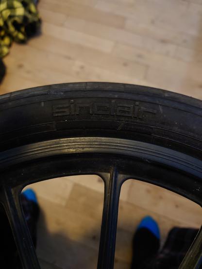 A picture of a bicycle like tyres on a plastic wheel with the square Sinclair logo in raised letter on it.