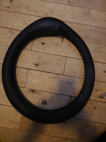A picture of a rubber inner tube showing the tube tapering outwards going clockwise from the valve at the top before really bulging out as it meets back up with the valve.