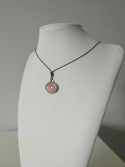 a silver pendant with transparent oval stone and black cord