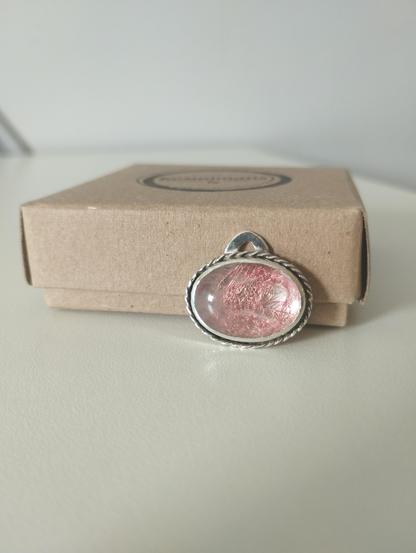a silver pendant with transparent oval stone. it has a dangled copper wire underneath the stone