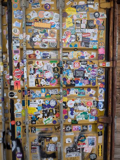 A shipping container door full of stickers. There's two Nett Hier from Baden Württemberg