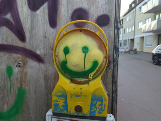The picture shows a construction light with a smiley painted on it. It looks like the face is crying with a smile.