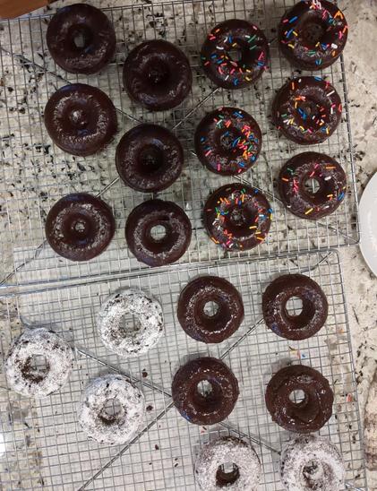 Picture of assorted chocolate donuts on a kitchen counter.