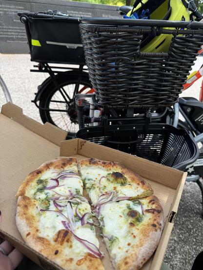 Pizza (pesto, cheese, onion) with bikes in the background