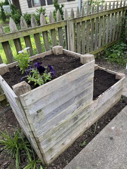 Raised garden bed with a few flowers and seeds planted in it.