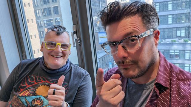 Photo of Myriam Joire (@tnkgrl, left) and Michael Fisher (@captain2phones, right) sitting in front of a larger window with the Manhattan skyline in the background
