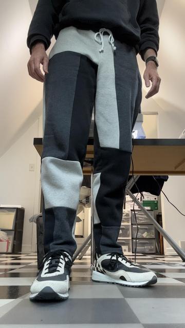 Me in my craft room, wearing color-blocked sweatpants and black-and-white striped sneakers, front view.