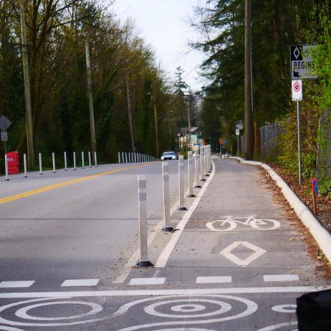 Riverside Dr at Windridge Dr, looking south. The bike lane is separated from cars by flex-posts.
