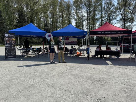 Photo showing 3 tents at Sunrise Park. Two HUB members are standing in front of the tents. The Bike Repair Café is on the left.