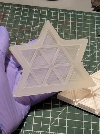 A translucent silicone mold in the shape of a stylized maple leaf, segmented into triangles.