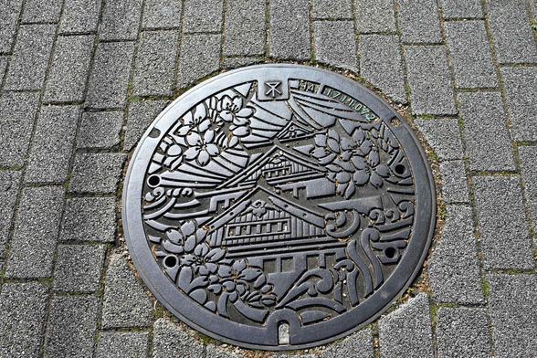 A manhole cover showing Osaka castle surrounded by cherry blossoms