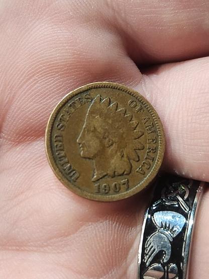 a hand holds a 1907 US penny