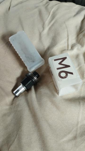 Petite boîte en plastique, elle est ouverte et à côté se trouve l'embout qui permet de sertir un insert avec un pas de vis interne. Il est marqué m6 sur une des parties
