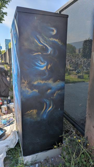 Peinture d'une merveilleuse nébuleuse sur fond noir avec des touches de bleus et or, recouvrant un boîtier électrique.