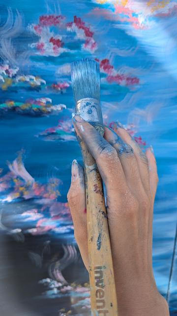 Close up de la peinture des nénuphars sur le boîtier électrique avec en premier plan la main de l'artiste, taché de peinture et tenant le pinceau.