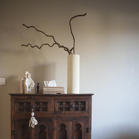 Photographie dans le salon de Latifah, un élément de décor, une commode, dessus posé un vase et de petits objets, la lumière est douce.