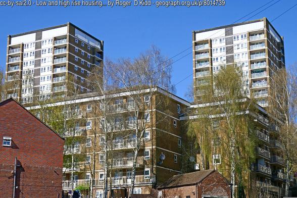A view of one medium rise and two high-rise apartment blocks against a vivid blue sky. The styles are "textured brutalist"