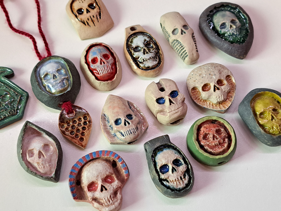 Variation of stoneware skull pendants laid out on a white table.