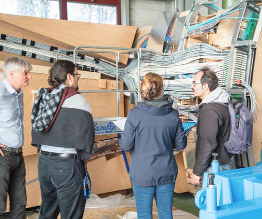 Personnes du public en visite à l'expérience CMS au CERN.
On voit ici des câbles au mur parfaitement rangés et distribués vers une partie de l'électronique.
