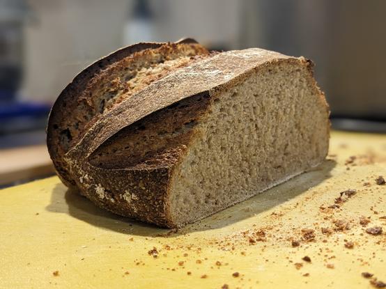 Half of a brown bread loaf (boule) on a cutting board.
