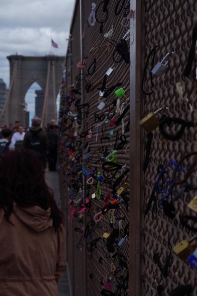 Various locks hung onto one of the walls (covering the vertical cables) of Brooklyn Bridge. The (east) bridge tower can be seen in the background.