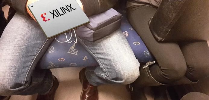 A photo of a man's legs sitting in the Stockolm metro. The legs are spread and the woman sitting next to him is forced to squeeze her legs by pushing herself.

The top of the man's legs are hidden by the image of a BGA-type electronic component with Xilinx printed on it.

Image source from wikipedia : https://fr.wikipedia.org/wiki/Manspreading