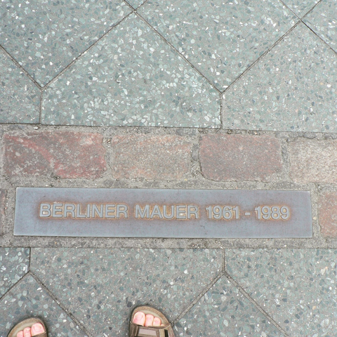 a row of double bricks let into a paving stone surface, indicating the location of the Berlin Wall, 1961-1989