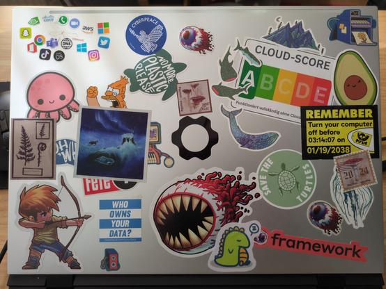 A laptop lid with lots of stickers on it.