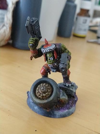 A snarling space work wielding two hsndguns, standing in a pile of rocks and a scratch built tire.