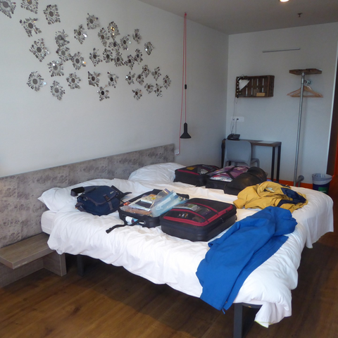 The interior of a hostel double room, with suitcases open and jackets neatly arrayed.