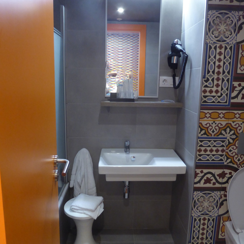 A colourful three-piece bath with sink, mirror and Spanish tile on the wall.