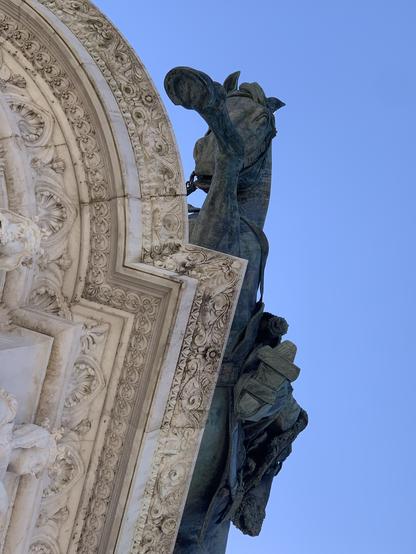 Die Reiterstatue von Viktor Emmanuel dem Zweiten von unten. Man sieht die Hufeisen des Pferdes und die Steigbügel des Reiters über der Stiefelsohle.