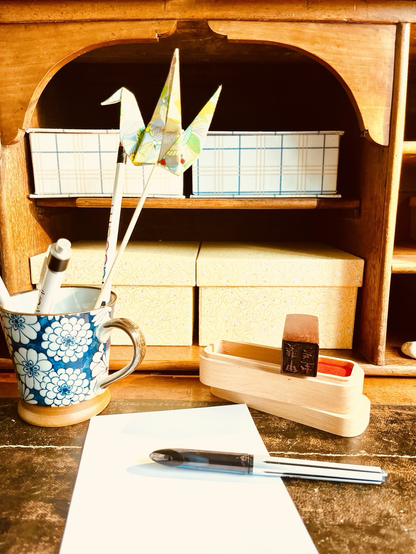 Photo de mon bureau d’atelier avec une grue en origami , une feuille et un stylo