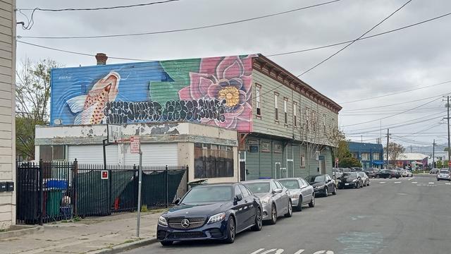 A mural on the side of a wood-frame building, with a (Koi?) fish and a flower.