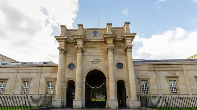 Photograph of Oxford University Press building, a stately gate with colonnades (image via The Bookseller, used under fair use as illustrative material on a non-monetized academic blog)