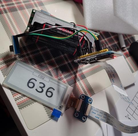 Oben im Bild sind Akkus erkennbar. Daran angeschlossen ein Mikrocontroller, ein Sensor und ein eInk-Display. Auf dem Display steht CO2 und die Zahl 636.