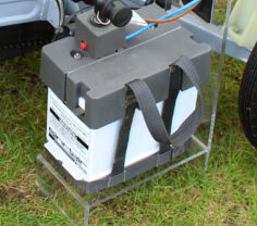 A picture of the original 12 volt 80 AH lead acid Sinclair C5 battery with a grey top with a small unit on it for the "ignition" key and kill switch.
