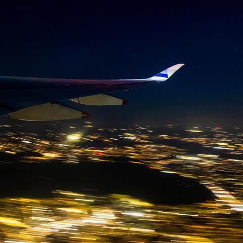 A view out of the window of a China Airlines Airbus A350-900 whilst departing from Heathrow Airport, with a long enough exposure to make all the lights of the city below turn into streaks of light.