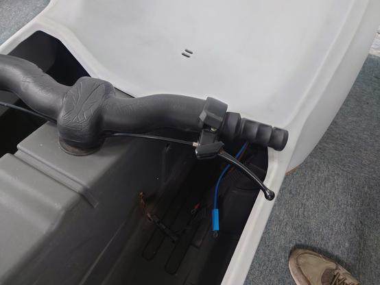 A picture of the rear left footwell, showing a clip for a fabric strap and one blue and one brown wire coming out of the rear compartment, with hoop fittings crimped on each wire so I could attached it to a power supply.