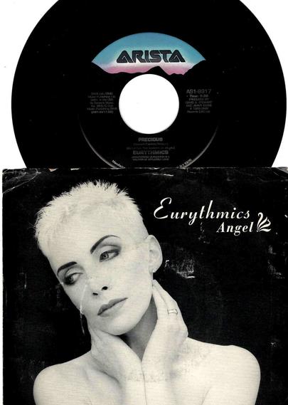 Top half of the photo shows the Arista record label logo on the 7" single of "Angel" by Eurythmics. The title is listed as "Precious" (the b-side). Bottom half is the black and white picture sleeve showing Annie Lennox's head and shoulders and her hands posed on either side of her neck.