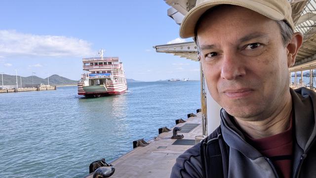 A selfie. In the background, Meon. It's a small ferry. It has red and white horizontal stripes.