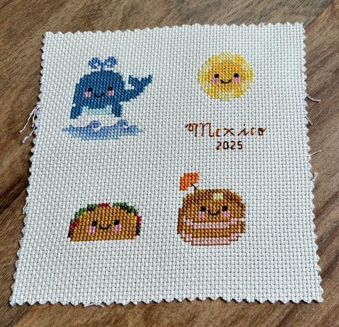 A group of four cross stitched designs with backstitched text reading: Mexico 2025.The designs include a happy faced sun,  a spouting whale, a happy faced taco and a plate full of pancakes topped with a happy face and a tiny, orange paper umbrella.