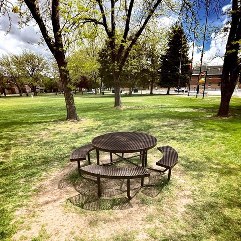 An outdoor table next to a soccer field with all the grass trampled down to dirt around it.