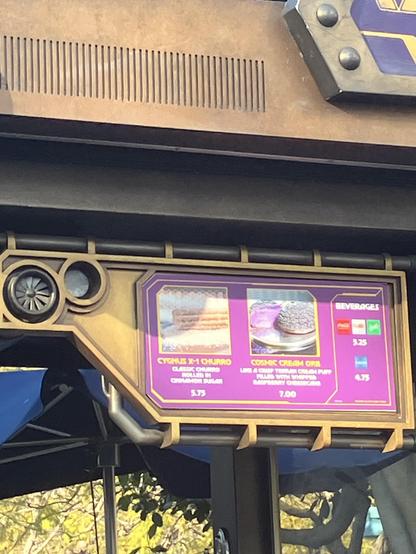 Photograph of a sign. The purple/pink sign has a photograph with the text “Cygnus X-1 Churro” along with a cookie offering and soda logos.