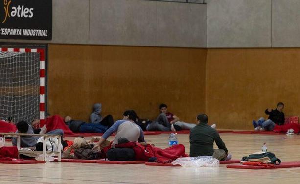 Gent pernoctant al pavelló de l'Espanya Industrial, a Barcelona, habilitat per a passatgers que no han pogut tornar a casa (EFE)
