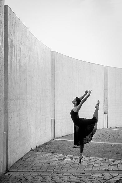Ballerina auf einem Bein auf Spitze stehend vor einer Betonwand